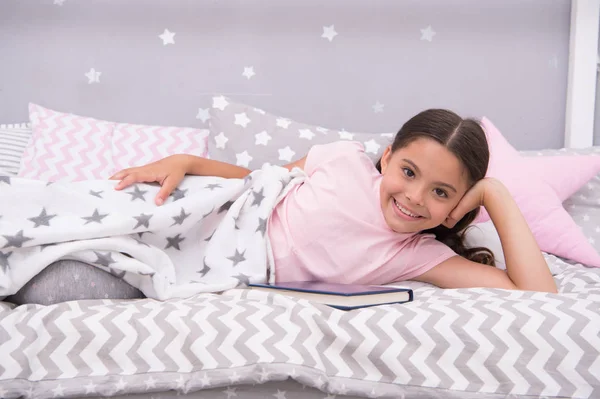 Satisfied with happy end. Girl child lay bed read book. Kid prepare to go to bed. Pleasant time in cozy bedroom. Girl kid long hair cute pajamas relax and read book. She likes kind stories about love — Stock Photo, Image