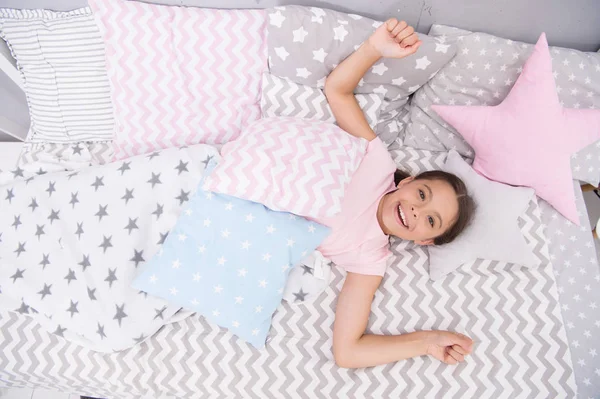 Wish her good morning. Girl child lay on bed her bedroom. Kid awake and full of energy. Pleasant time relax cozy bedroom. Girl kid relaxing in morning. Cheerful and wakeful concept