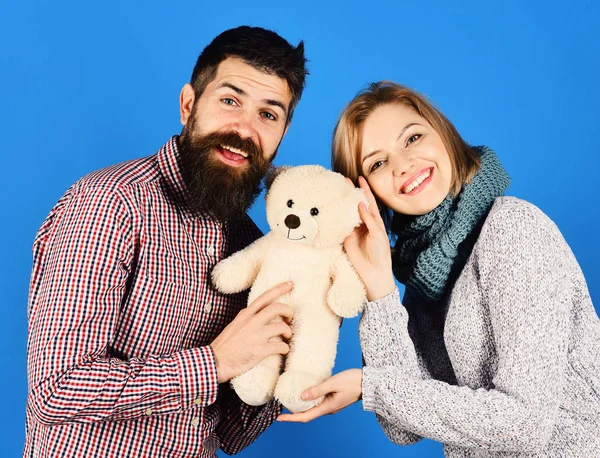 Girl and man with happy faces play with soft toy.