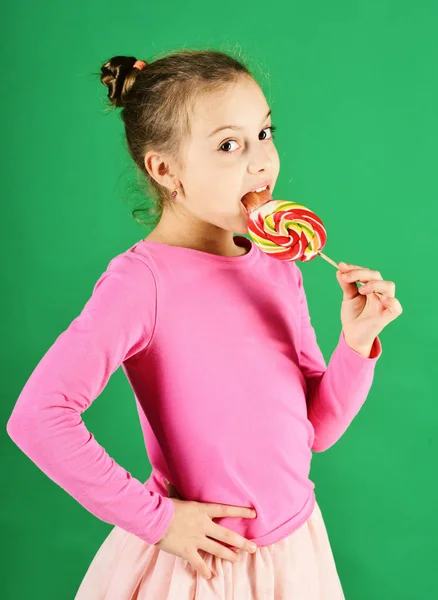 Meisje eet grote kleurrijke zoete karamel. Behandeling en snoep concept. — Stockfoto