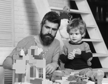 Arka planda oyuncakları olan baba ve çocuk blokları inşa ediyor.