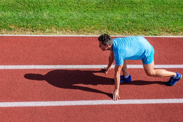 Running tips for beginners. Man athlete stand low start position at stadium path. Beginning of new lifestyle habit. Runner ready to go. Athlete runner prepare to race at stadium. How to start running — Stock Photo, Image