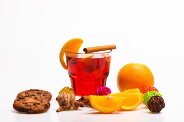 İçki sezon kavramının. İçki veya tarçın, turuncu meyve ve çerez çikolata damla içecek. Cam mulled şarap veya içki yakınındaki beyaz arka plan üzerinde sulu turuncu meyve ile yakın çekim