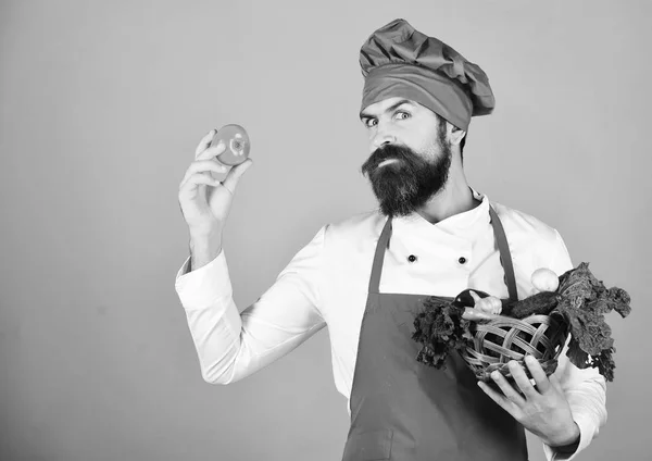 Людина з бородою на червоному тлі. Шеф-кухар тримає салат, часник — стокове фото