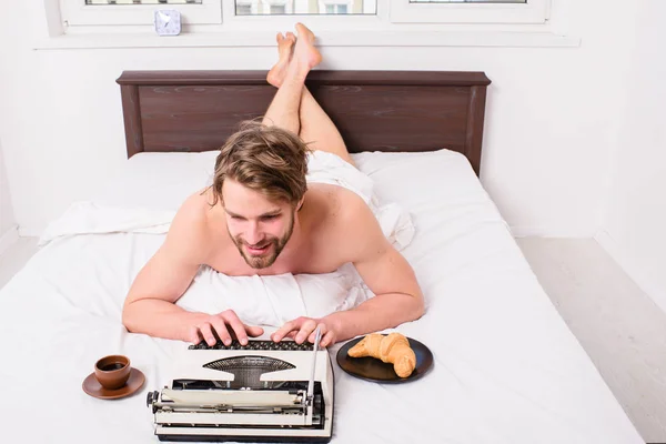 Writer romantic author used old fashioned typewriter. Author having breakfast in bed eat croissant and coffee. Pleasant occupation. Morning inspiration. Man writer lay bed bedclothes working book