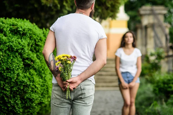 Eerste indruk is altijd belangrijk. Man verbergt bloemboeket achter rug terwijl wacht meisje romantische datum. Verrassing voor haar. Bijeenkomst voor datum park achtergrond (echt) paar. Guy bereid verrassing voor vriendin — Stockfoto