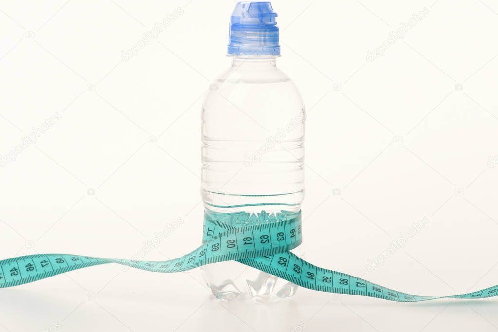 Water bottle tied with cyan measure tape on white background