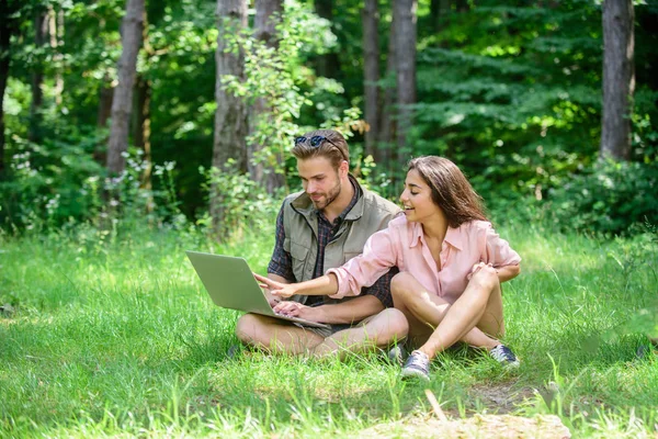 Uomo e ragazza che guardano lo schermo del portatile. Un paio di giovani trascorrono il tempo libero all'aperto con il computer portatile. Le moderne tecnologie offrono l'opportunità di essere online e lavorare in qualsiasi condizione ambientale. Natura miglior spazio di lavoro — Foto Stock