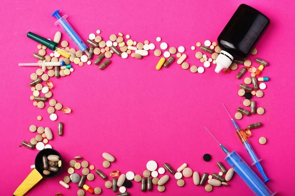 Set of colorful pills scattered on pink background