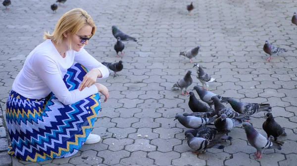 Mädchen füttert Taubenvögel. Tauben warten auf dem Stadtplatz auf Leckereien. Großzügigkeit teilen. Mädchen blonde Frau entspannen Stadtplatz und Tauben füttern. Touristin oder Bürger werfen Krümel für Tauben — Stockfoto