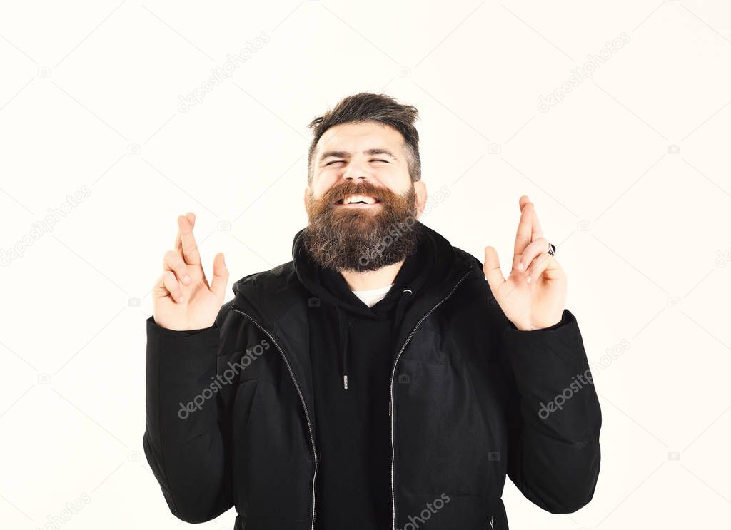 Man with beard and closed eyes crosses fingers, gesture