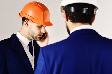 İnşaat, mühendislik, işletme, mimari, ortaklık, meslek kavramı. Ciddi yüzleri olan miğferli mühendisler. Mimarlar projeyi tartışır. İş toplantısında akıllı telefonu olan bir çalışan.