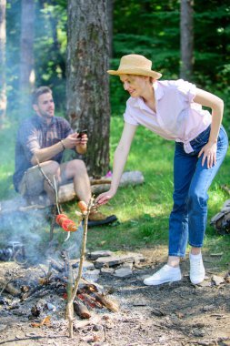 Yemek yemek kamp ateşi doğa arka plan, hasır şapkalı kız. İpuçları her kamp kamp ateşi pişirme hakkında bilmeniz gerekenler. Kamp ipuçları. Sopa üzerinde pişirmek için gıdalar. Kamp ateşi pişirme geliştirmek için pratik öneriler