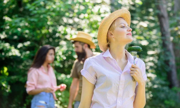 Girl holds fork with cucumber. Friends eating food picnic. Nature conditions cause great appetite. Lady vegetarian in straw hat eats green organic cucumber. Vegetable organic nutrition for vegetarian — Stock Photo, Image