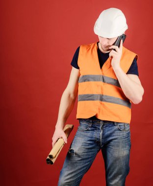 Adam, konuşan, kırmızı arka plan kask içinde foreman. Planı düzeltmek için arama mühendis mimar. İletişim kavramı. Mühendis, mimar, Smartphone cep telefonu ile ayrı tutma planları süre meşgul yüzünde konuşuyor.