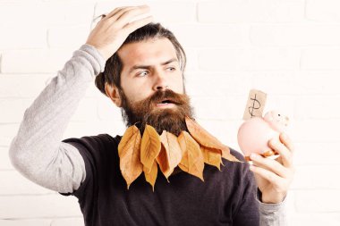 yakışıklı adam şık bıyık ve sonbahar uzun sakal sarı yapraklarda pembe domuz domuz banka ile ciddi yüzünde beyaz tuğla duvar arka planda bir şey unuttum sakallı