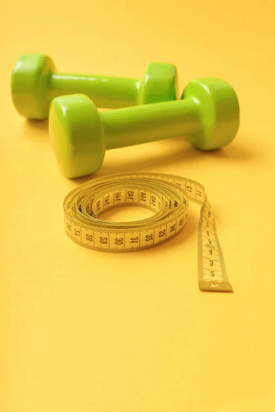 Atletismo e conceito de perda de peso. halteres na cor verde brilhante isolado no fundo amarelo — Fotografia de Stock