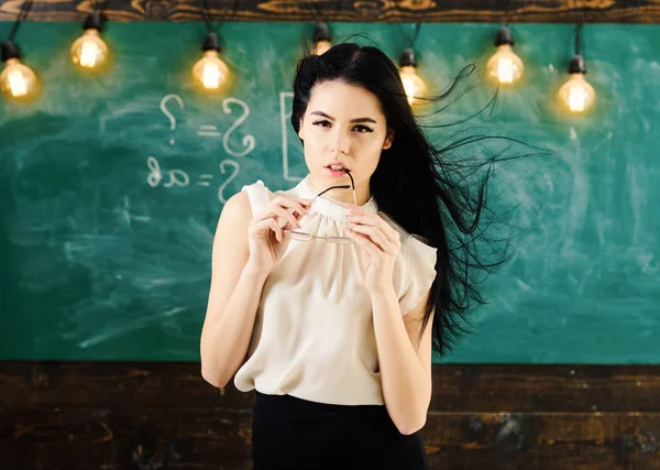 Profesor con gafas y cabello ondulado se ve sexy. Mujer con el pelo largo en blusa blanca se para en el aula. Señora estricta maestra en la cara de ensueño se para delante de pizarra. Sexy concepto de profesor . — Foto de Stock