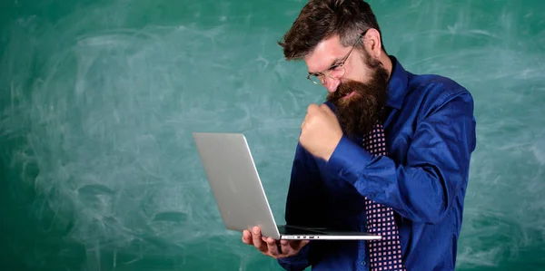 Technology blows his mind. Can not get used to modern technology. Teacher bearded man with modern laptop chalkboard background. Hipster teacher aggressive with laptop goes mad about modern technology — Stock Photo, Image