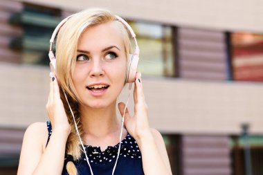 Defocused kentsel arka plan, kulaklıktan müzik dinleme genç bayan. Mutlu yüz kadınla müzik sever. Müzik ve eğlence kavramı