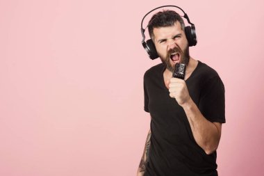 Adam mikrofon pembe, kopya alanı tutar. Sakallı DJ kulaklık takıyor. Müzik ve eğlence kavramı.