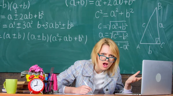 Profesor mujer sentarse mesa aula pizarra fondo. Sigo trabajando. Profesor ocupado con el papeleo y la investigación. Trabajar mucho más allá del día escolar actual. Maestro impactado cara seguir trabajando después de clases — Foto de Stock