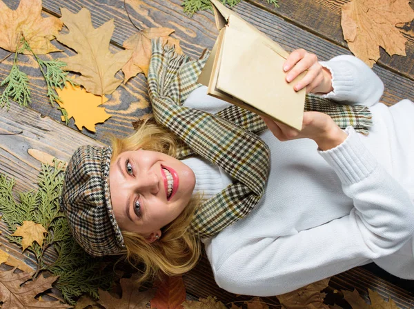 She likes detective genre. Woman lady in checkered hat and scarf read book. Girl in vintage outfit enjoy literature. What to read in autumn book list. Girl blonde lay wooden background with leaves