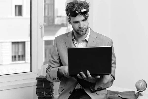 Homme d'affaires avec ordinateur portable et pile de livres sur fond de fenêtre — Photo