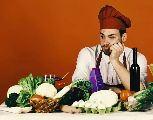 Koken werkt in keuken in de buurt van tafel met groenten en gereedschappen. — Stockfoto