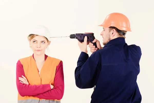 Constructeur, réparateur fait un trou dans la tête féminine. Femme avec le visage ennuyé dans le casque ignorant mari ennuyeux elle . — Photo