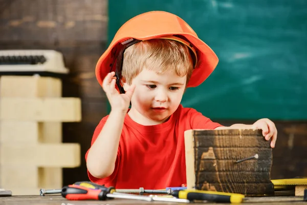 Criança no capacete bonito jogando como construtor ou reparador, reparação ou artesanato. Conceito de artesanato. Criança no rosto ocupado joga em casa na oficina. Kid boy jogar como faz-tudo . — Fotografia de Stock