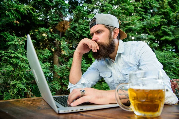 Betting and real money gaming. Brutal man leisure with beer and sport game. Football fan bearded hipster make bet sport game laptop. Bet on world championship. Guy sit terrace outdoors with beer
