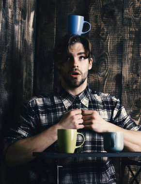 Ahşap arka planda bardakları tutan yakışıklı adam.