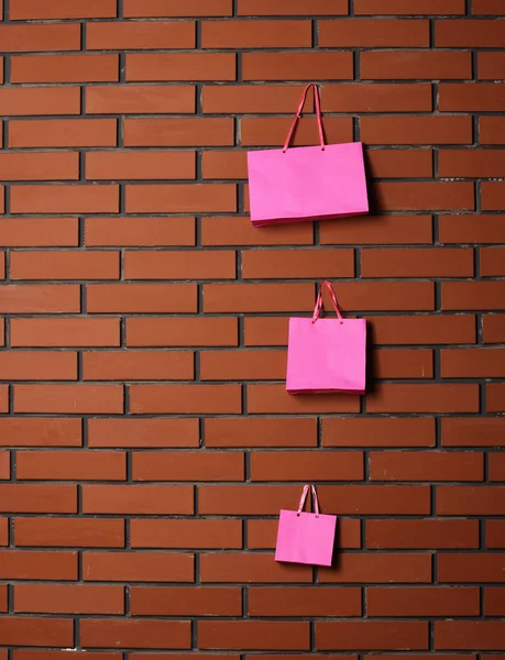 textured brick wall background with little cute pink shopping bag hang on it, copy space