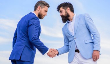 El sıkışırken girişimcilerin başarılı anlaşma sembolü. İş ortağı doğrulayan anlaşma hareketi. Erkekler resmi titreyen eller mavi gökyüzü arka plan uygun. Onaylı iş anlaşması her iki ortak tarafından kabul