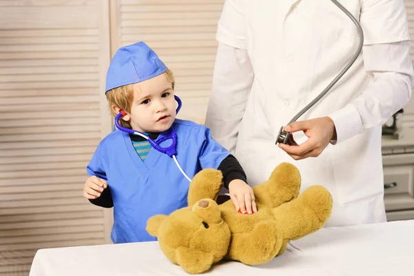 Hombre y niño sostienen estetoscopios sobre fondo de madera . — Foto de Stock