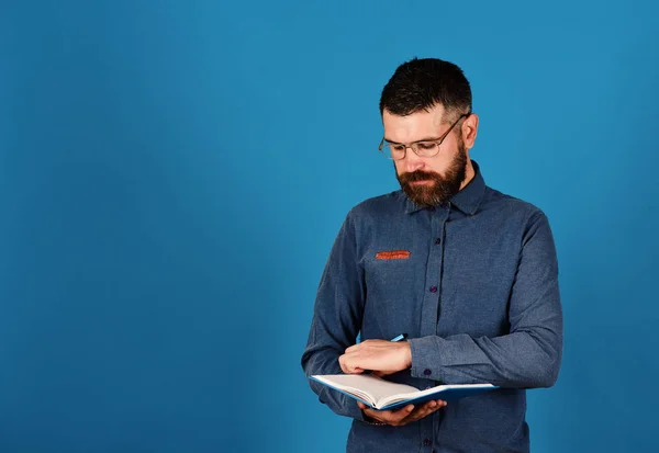 Человек с бородой читает синюю книгу на синем фоне . — стоковое фото