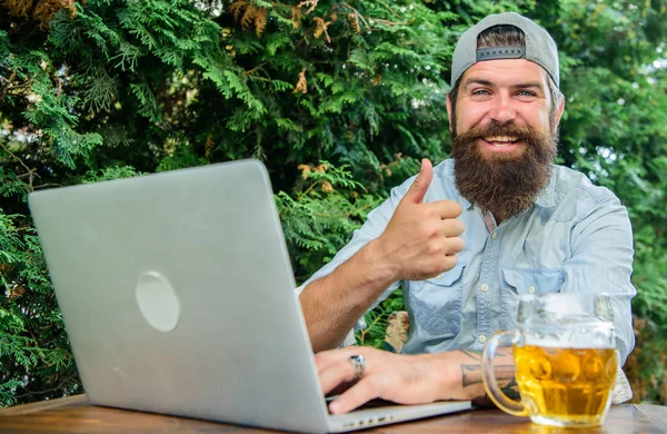 Football fan bearded hipster make bet sport game laptop. Guy sit terrace outdoors with beer. Betting and real money gaming. Brutal man leisure with beer and sport game. Bet on world championship