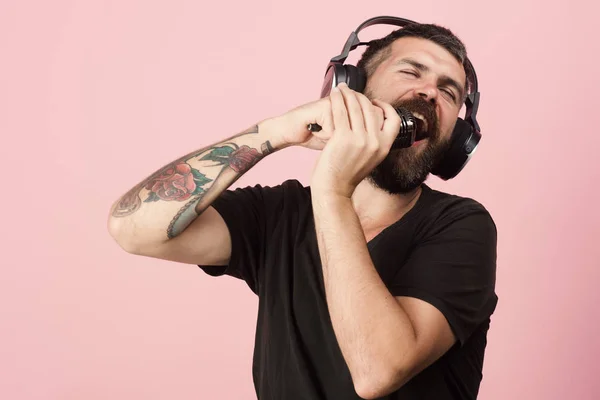 Dj con barba usa auriculares. El hombre canta sobre fondo rosa , — Foto de Stock