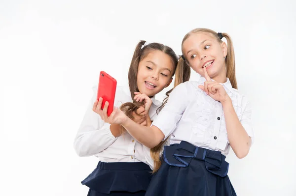 Chicas uniforme escolar tomar teléfono inteligente selfie. Posando para tomar una foto perfecta. Ocio femenino. Las chicas solo quieren divertirse. Colegialas lindo peinado utilizar el teléfono móvil o teléfono inteligente para compartir fotos — Foto de Stock