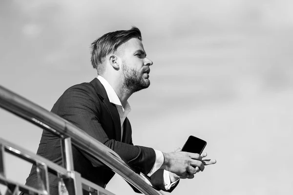 Hombre de negocios con teléfono inteligente en la terraza en el cielo azul, comunicación de negocios — Foto de Stock