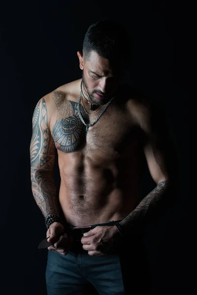 Hombre barbudo sin camisa con el torso en forma. Hombre con diseño de tatuaje en la piel. Modelo de moda hebilla cinturón de cuero en jeans. Deportista con seis paquetes y ab. Fitness con deporte y bodycare — Foto de Stock