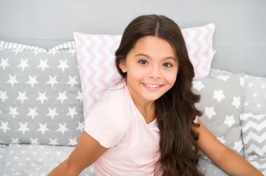 Uzun kıvırcık saçlı, gri iç görünüşlü bir kız çocuğu. Mükemmel kıvırcık saçlı çocuk şirin görünüyor. Saçlarını parlak ve sağlıklı tutmak için organik yağlı saç kremi ya da maske kullanıyor. Güzellik salonu ipuçları