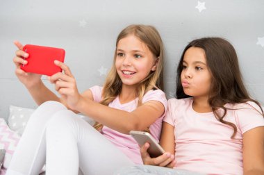 Çocuklar yatak odasında selfie çekiyor. Pijama partisi konsepti. Kız kıza mutlu bir çocukluk. Akıllı telefonlu uzun saçlı kızlar modern teknoloji kullanır. Hadi selfie çekelim. Arkadaşlarınızın sosyal ağ fotoğraflarını gönderin
