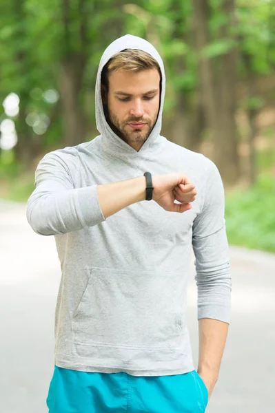 Check time his best score. Man athlete busy face check fitness tracker nature background. Athlete with bristle looks at fitness tracker or pedometer. Sportsman training with pedometer gadget