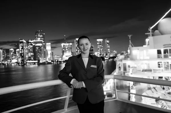 Mujer mayordomo a bordo del barco por la noche en Miami, EE.UU. Mujer sensual en chaqueta de traje en el horizonte de la ciudad. Transporte por agua, transporte. Viajar por negocios. Lujuria, aventura, descubrimiento, viaje — Foto de Stock