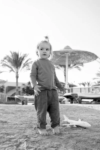 Child play on sand beach. Small boy with plane toy outdoor. Kid have fun on summer vacation. Imagination, freedom and dream concept — Stock Photo, Image