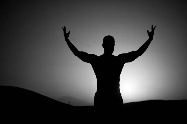 Günbatımı gökyüzü üzerinde uygun siluet olan adam. Sporcu doğal peyzaj üzerinde yükseltilmiş el ile. Atlet göstermek güç. Yaz dusk olarak çalışma. Spor, sağlık ve welness kavramı — Stok fotoğraf