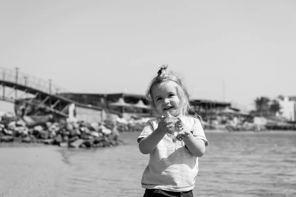 어린 소년 바다 해변에 포탄과 미소. 맑은 바다에 조개와 어린이 놀이. 자유, 발견과 모험 여름 휴가 바다에. 행복 한 유년 시절 개념 — 스톡 사진