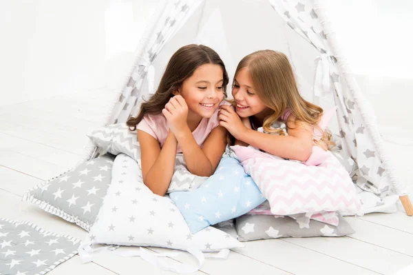 Share secrets concept. Girls cute children lay relaxing in teepee bedroom. Cute space for leisure. Modern interior includes comfortable teepee houses. Secret conversation between closest friends